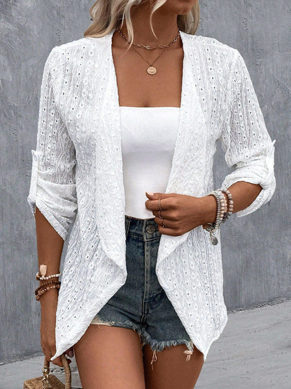 Femme portant un cardigan blanc en dentelle, débardeur blanc, short en jean, accessoires en perles, style décontracté chic, mode estivale tendance.