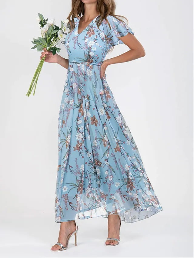 Robe longue bleue à fleurs, manches courtes, portée par une femme tenant un bouquet. Mode féminine élégante, tendance printemps-été.