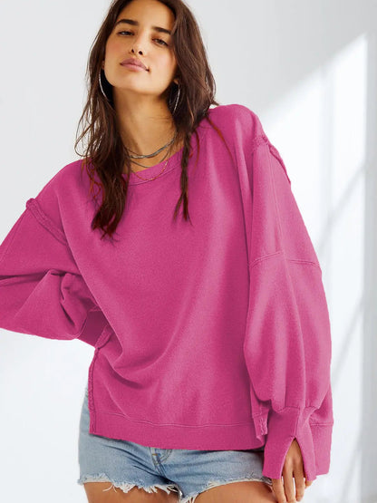 Femme portant un pull rose ample et un short en jean, posant dans un intérieur lumineux. Mode décontractée, tendance automne, style confortable.