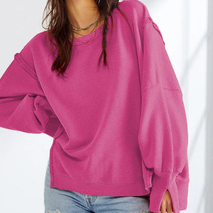Femme portant un pull rose ample, manches longues, avec un jean décontracté. Mode féminine, style décontracté, tendance automne-hiver.