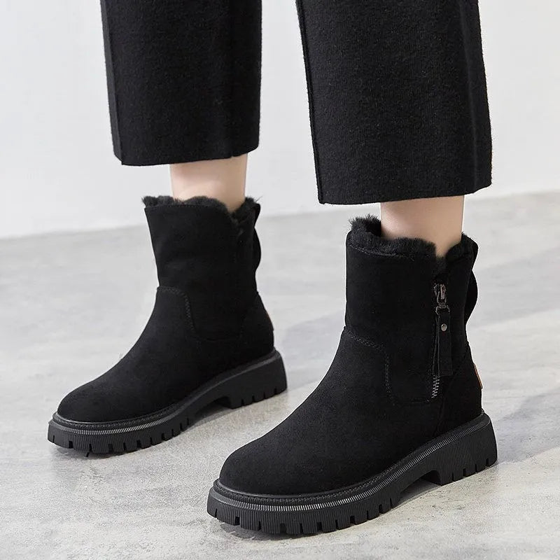 Bottes d'hiver noires en daim avec doublure en fourrure, fermeture éclair latérale, semelle épaisse antidérapante, portées avec un pantalon noir.