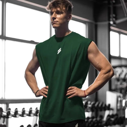 Ung mand i grøn trænings-T-shirt står i fitnesscenter, omgivet af vægte. Fitness, styrketræning, sund livsstil, muskuløs fysik.