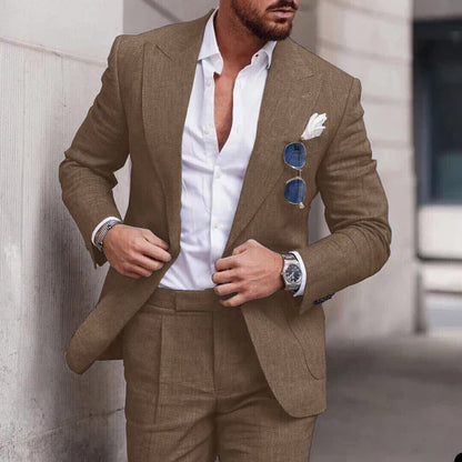 Homme en costume marron élégant, chemise blanche ouverte, lunettes de soleil accrochées, montre argentée, style mode masculine moderne.
