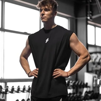 Ung mand i sort træningstøj står i fitnesscenter, omgivet af vægte. Muskuløs krop, fokuseret blik. Fitness, styrketræning, sund livsstil.