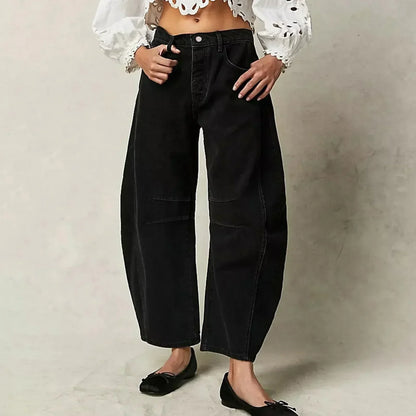 Pantalon large noir femme, taille haute, avec poches, porté avec un haut blanc à manches longues brodées. Mode décontractée, tendance actuelle.