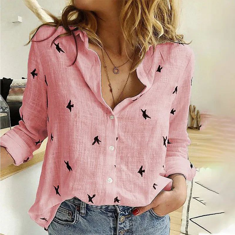 Femme portant une chemise rose à motifs d'oiseaux noirs, manches retroussées, col ouvert, associée à un jean décontracté. Mode féminine tendance.