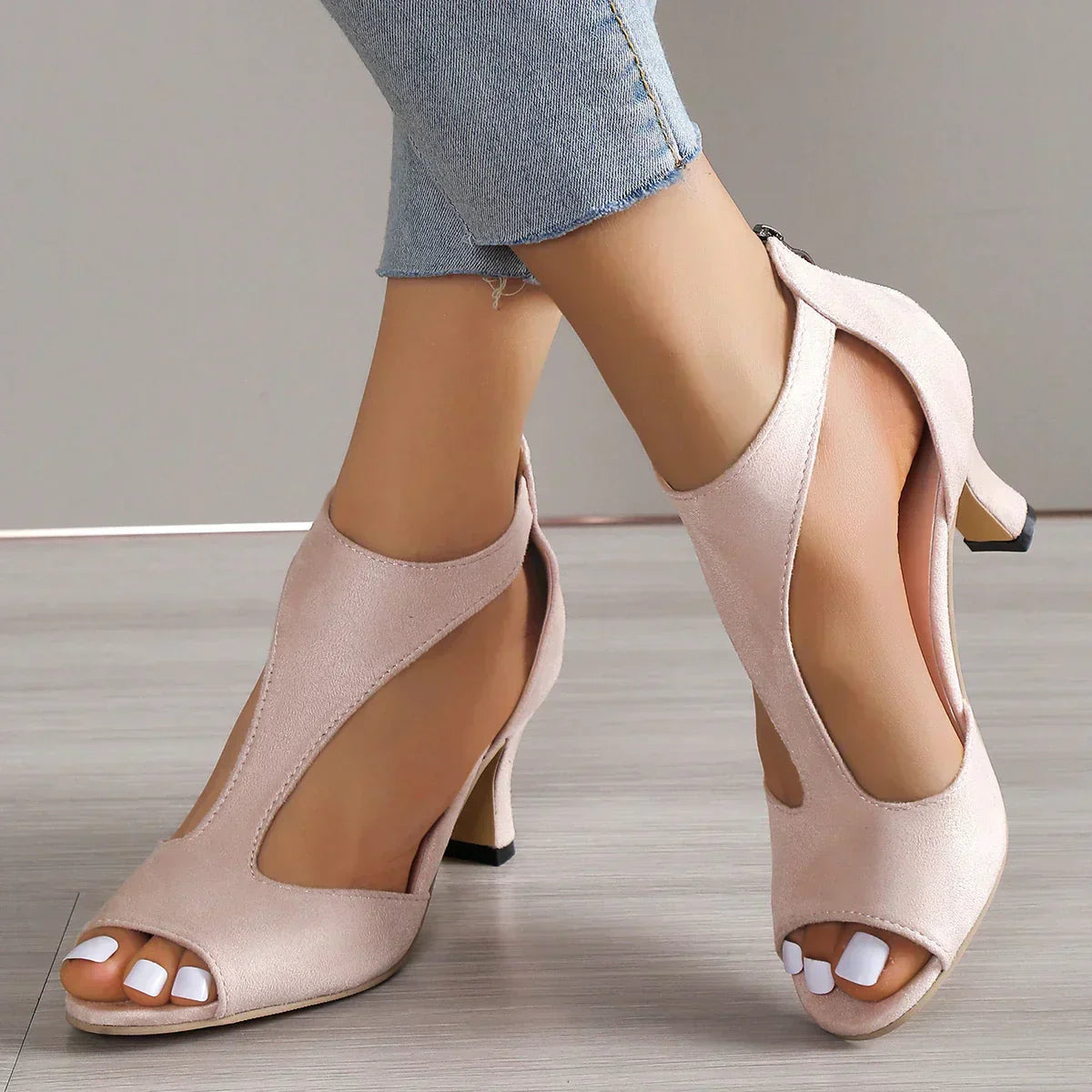 Escarpins roses à talons hauts, ouverts aux orteils, portés avec un jean ajusté. Chaussures élégantes pour femmes, parfaites pour une tenue chic.