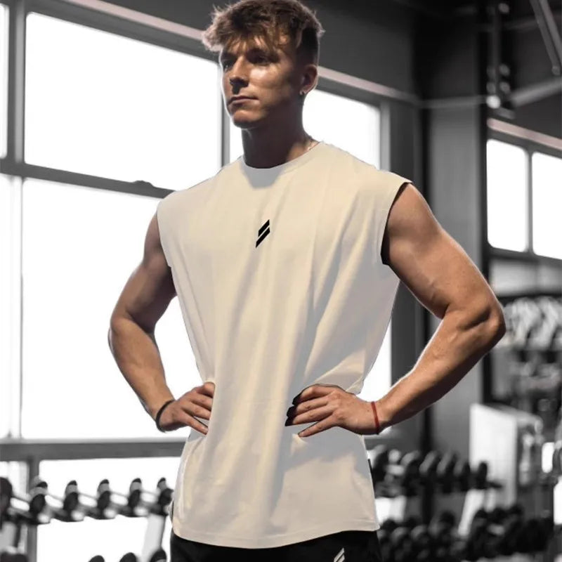 Ung mand i hvid tanktop træner i fitnesscenter, omgivet af vægte og træningsudstyr. Fitness, styrketræning, sund livsstil.