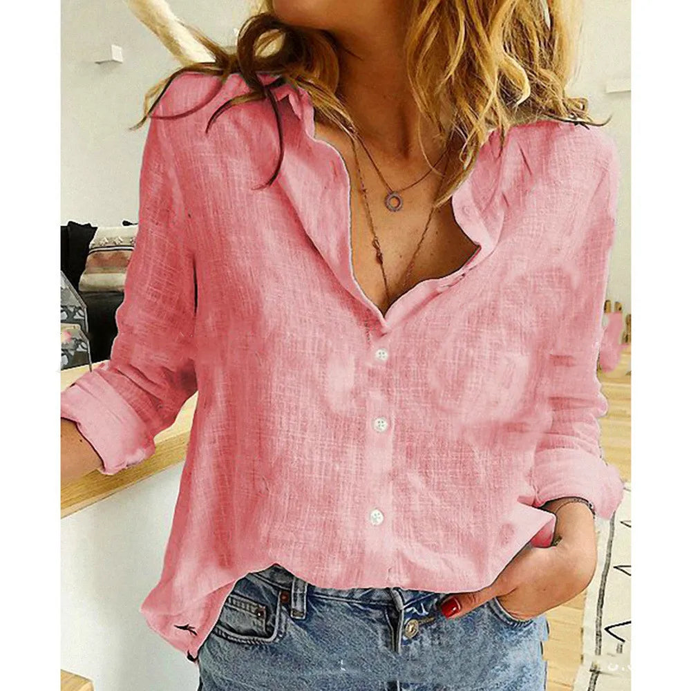 Femme portant une chemise en lin rose, manches retroussées, avec un collier délicat, posant dans un intérieur moderne. Mode décontractée chic.