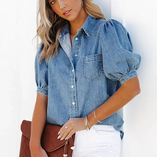 Femme portant une chemise en jean à manches bouffantes, tenant une pochette marron. Mode décontractée, style denim, tendance féminine.