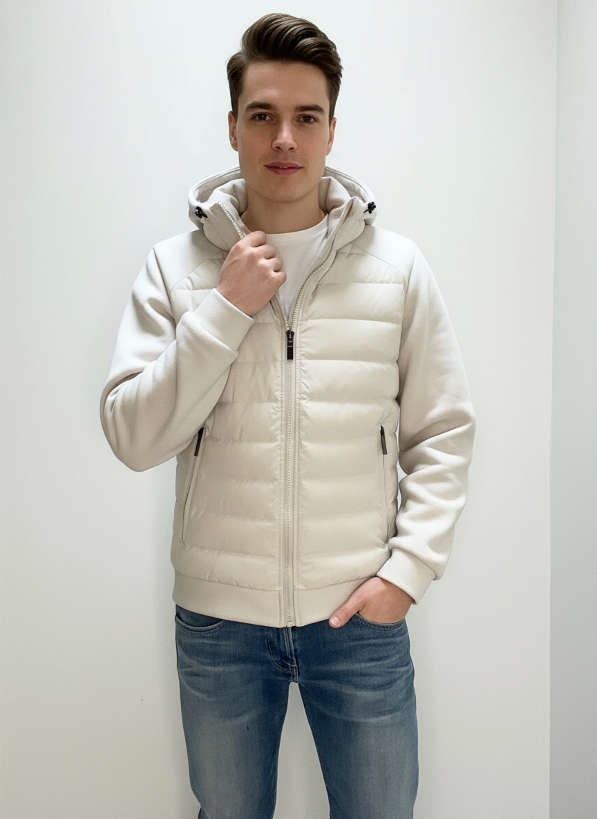 Ung mand iført hvid dunjakke og blå jeans, står mod hvid baggrund. Moderne herremode, vinterjakke, casual stil, komfortabelt tøj.