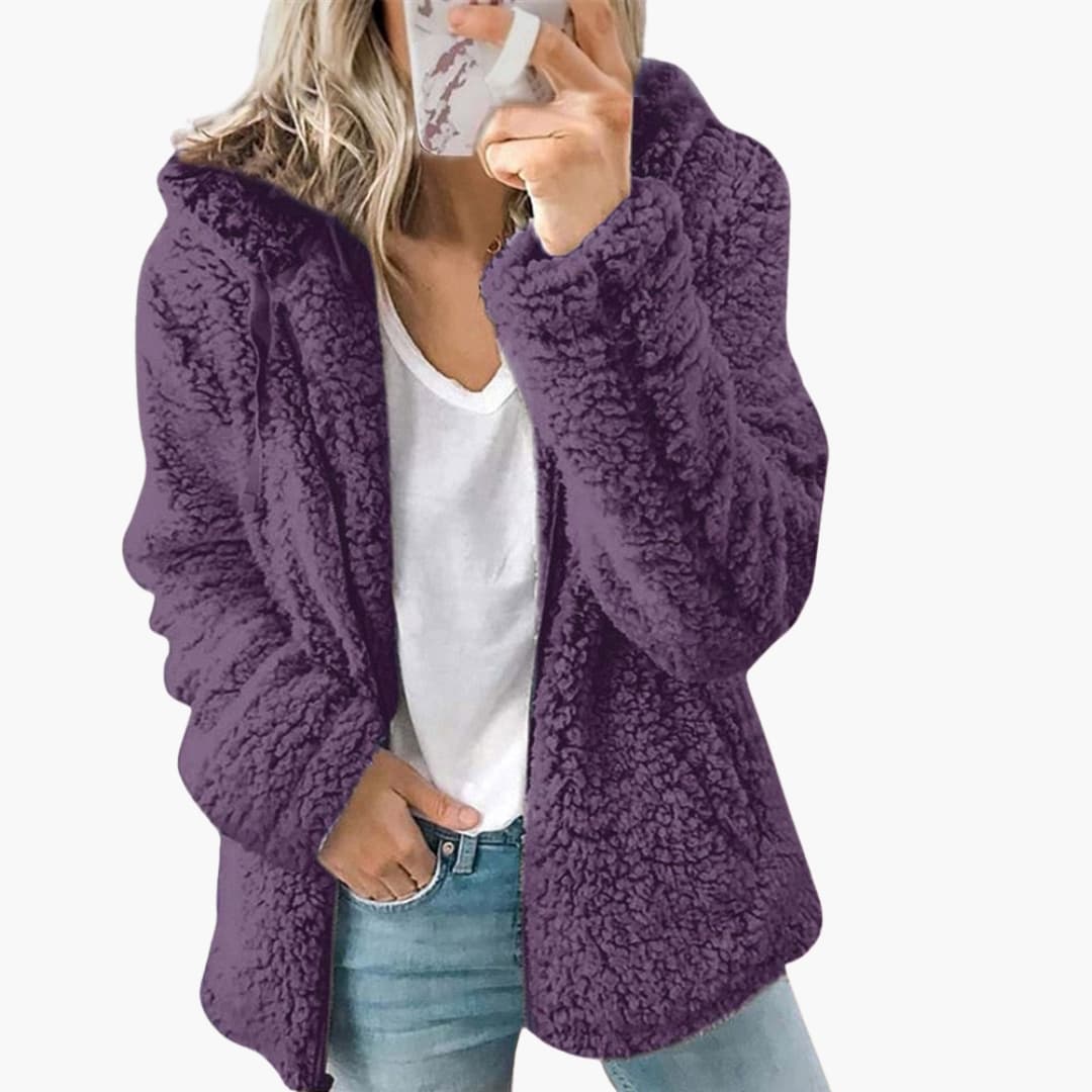 Femme portant une veste en fausse fourrure violette, tenue décontractée avec jean et t-shirt blanc, style automne-hiver tendance.