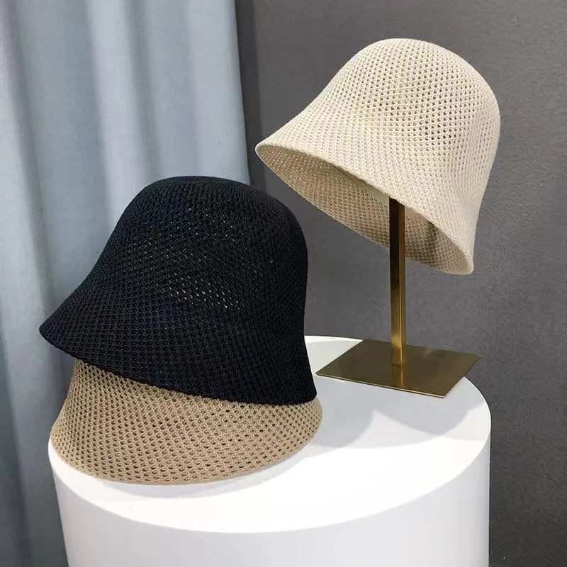 Deux chapeaux bob en maille, un noir et un beige, posés sur un présentoir moderne. Accessoires de mode élégants pour toutes saisons.