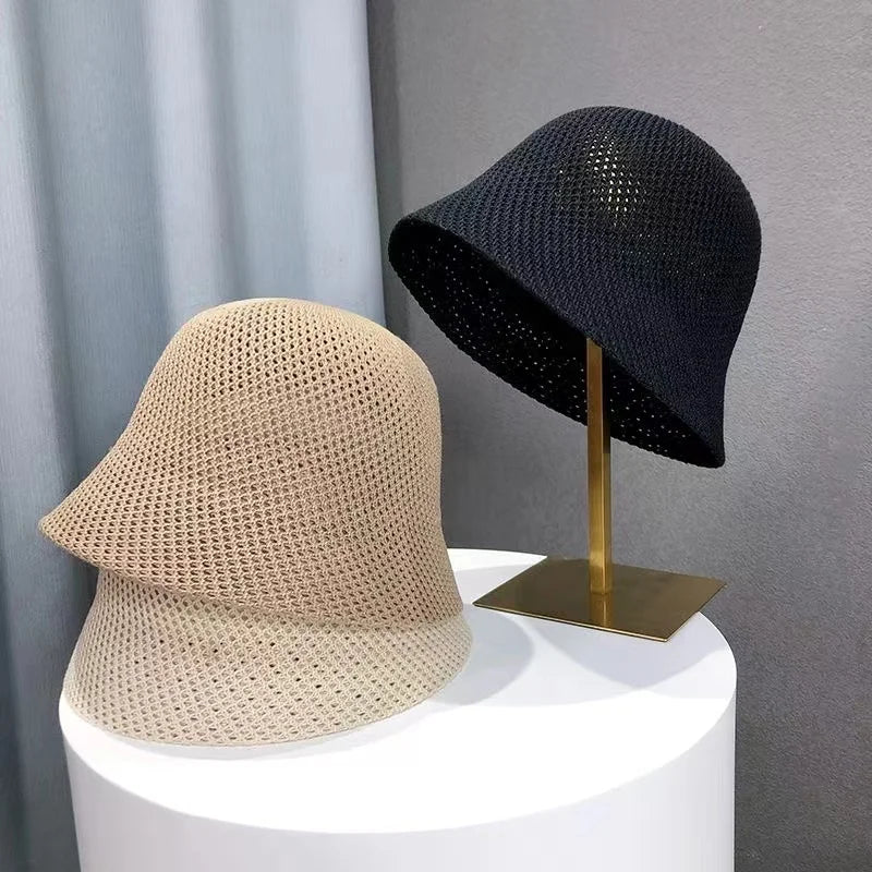Deux chapeaux cloche en crochet, beige et noir, posés sur un présentoir blanc et doré. Accessoires de mode élégants pour femmes.