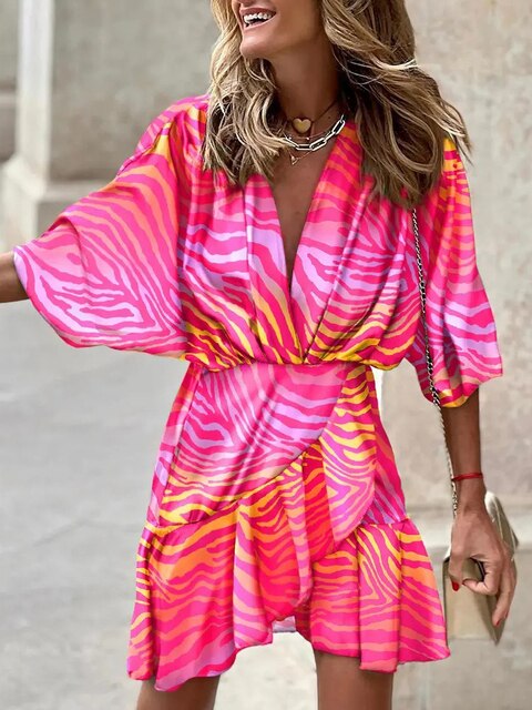Robe d'été rose et jaune à motifs zébrés, manches larges, col en V, portée par une femme souriante. Mode féminine, tendance estivale.