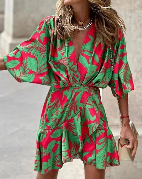 Robe d'été rouge à motifs feuillage vert, manches courtes amples, col en V, portée par une femme. Mode féminine, tendance estivale.