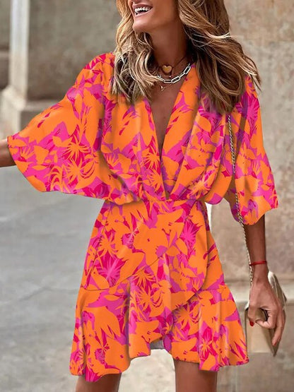 Robe d'été orange et rose à motifs floraux, manches évasées, col en V, portée par une femme souriante. Mode féminine, tendance estivale.
