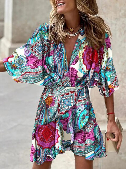 Robe bohème colorée à motifs paisley, manches larges, portée par une femme souriante. Mode estivale, style décontracté et tendance.