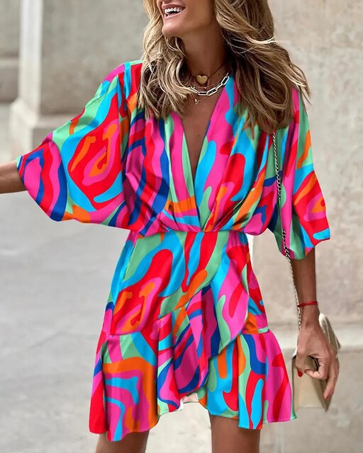 Robe colorée à motifs abstraits multicolores, manches courtes, portée par une femme souriante. Mode estivale, style vibrant et tendance.