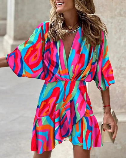 Robe colorée à motifs abstraits multicolores, manches courtes, portée par une femme souriante. Mode estivale, style vibrant et tendance.