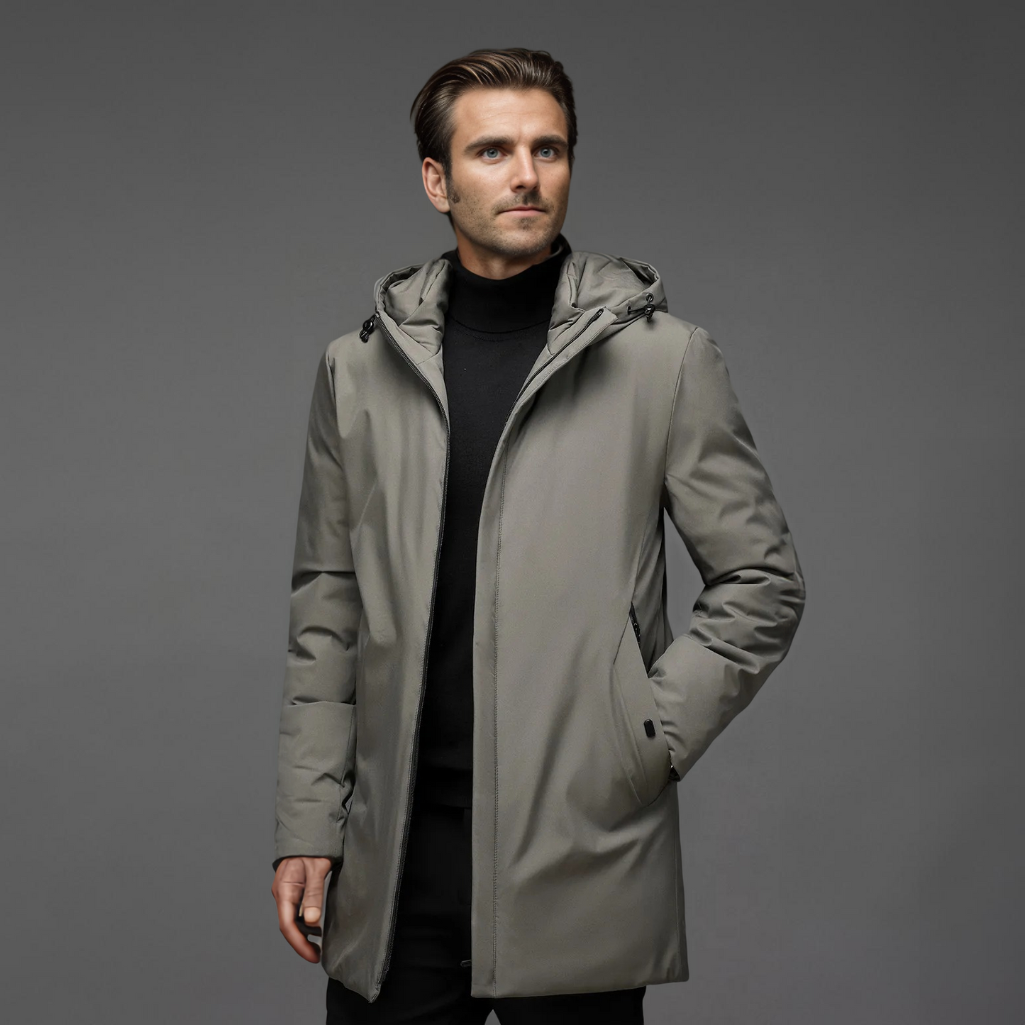 Homme portant un manteau gris élégant avec capuche, sur fond gris. Mode masculine, vêtement d'hiver, style moderne et sophistiqué.