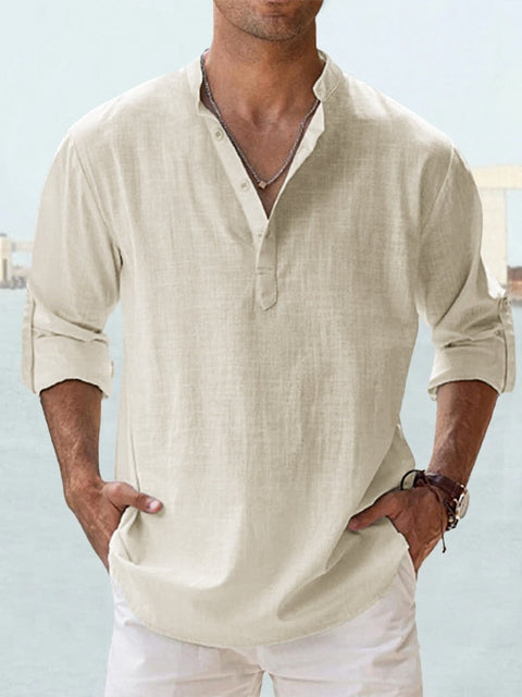 Homme portant une chemise en lin beige à manches longues retroussées, col boutonné, style décontracté, devant un fond flou. Mode masculine élégante.