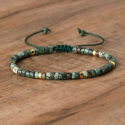 Grünes Steinarmband mit goldenen Akzenten auf Holzoberfläche, verstellbar, handgefertigt.
