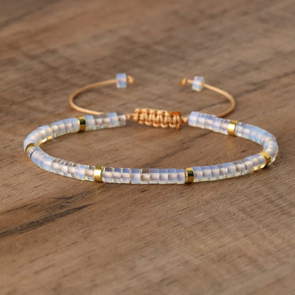 Perlenarmband mit goldenen Akzenten, verstellbar, handgefertigt, auf Holzoberfläche.