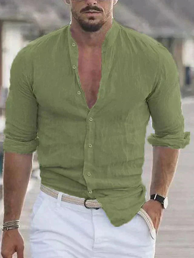 Homme portant une chemise verte en lin, manches retroussées, avec un pantalon blanc et une ceinture tressée, style décontracté estival.