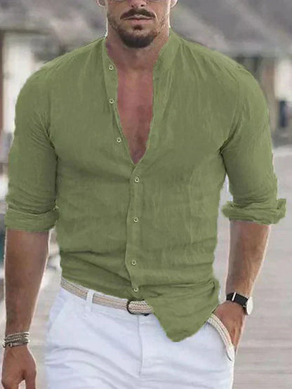 Homme portant une chemise verte en lin, manches retroussées, avec un pantalon blanc et une ceinture tressée, style décontracté estival.