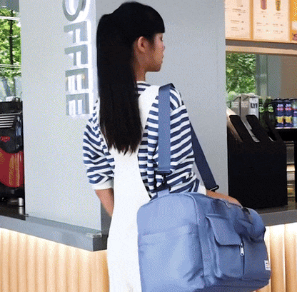 Frau mit blauer Reisetasche im Café, gestreiftes Shirt, moderne Reisetasche, Alltagstasche.
