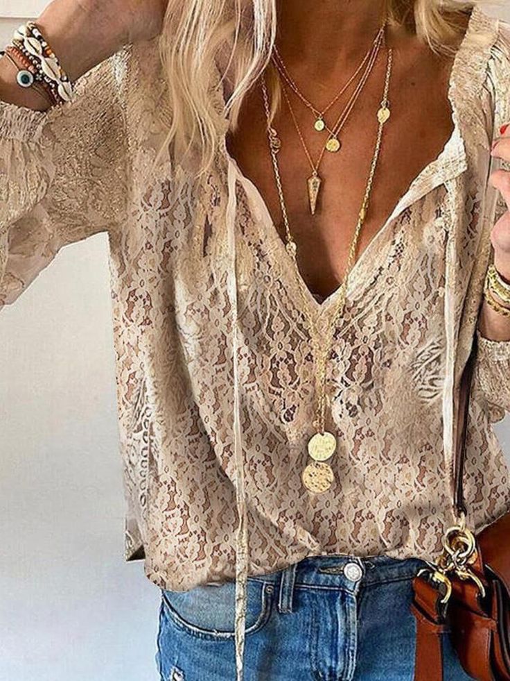 Blouse en dentelle beige élégante portée avec des colliers dorés superposés et un jean décontracté, style mode chic et tendance.