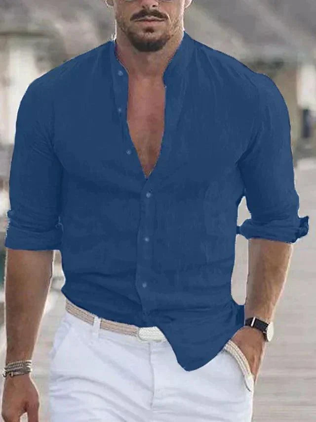 Homme en chemise bleue élégante, manches retroussées, marchant sur une promenade. Mode masculine, style décontracté chic, montre-bracelet noire.