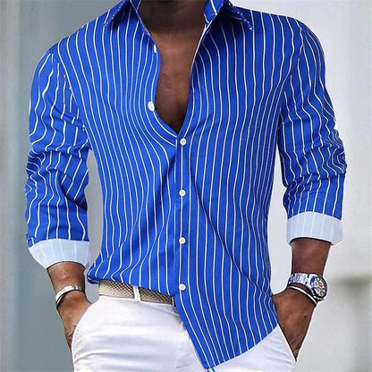 Chemise bleue à rayures blanches pour homme, manches longues, col ouvert, portée avec pantalon blanc. Mode masculine élégante et moderne.