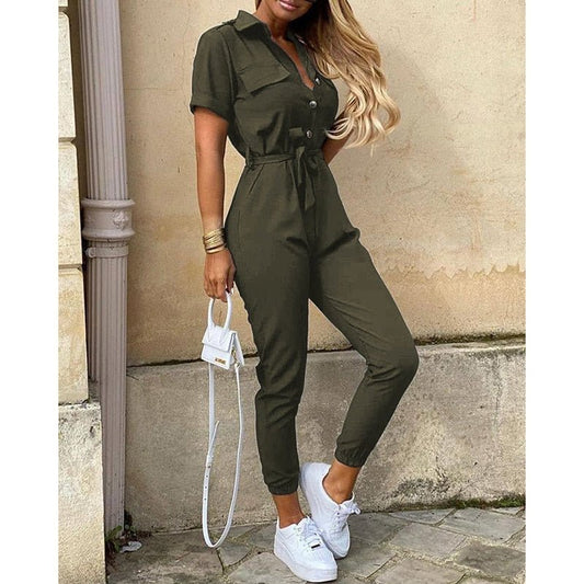 Combinaison verte élégante pour femme, manches courtes, ceinture à la taille, associée à des baskets blanches et un sac à main blanc tendance.