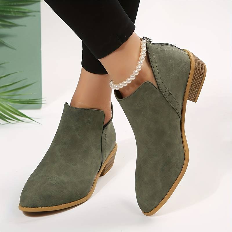 Bottines vertes en daim pour femme avec talon bas, portées avec un bracelet de perles. Chaussures élégantes et tendance, style automne-hiver.