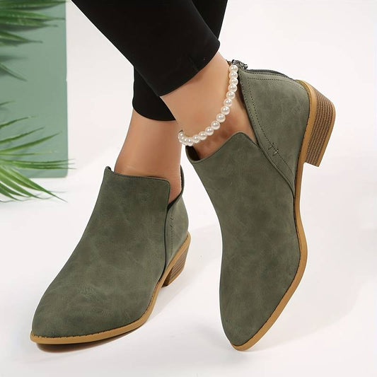 Bottines vertes en daim pour femme avec talon bas, portées avec un bracelet de perles. Chaussures élégantes et tendance, style automne-hiver.