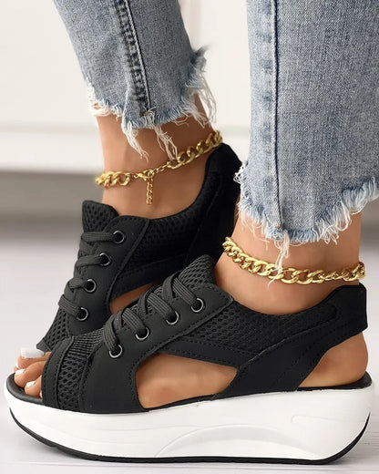 Chaussures compensées noires en maille avec semelle épaisse blanche, portées avec un jean déchiré et bracelet de cheville doré. Mode tendance femme.