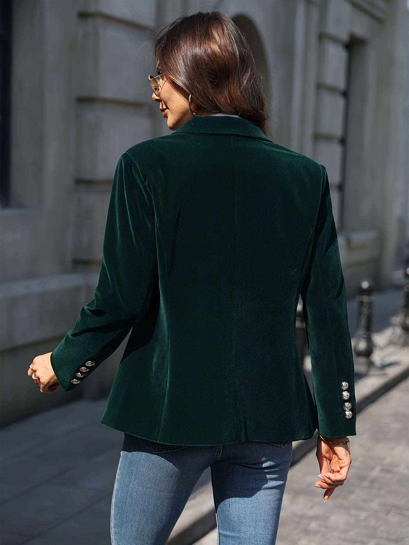 Femme portant une veste en velours vert foncé, boutons argentés, marchant en extérieur, style chic et élégant, mode automne-hiver.
