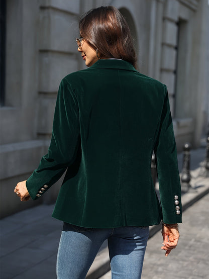 Femme portant une veste en velours vert foncé, boutons argentés, marchant en extérieur, style chic et élégant, mode automne-hiver.