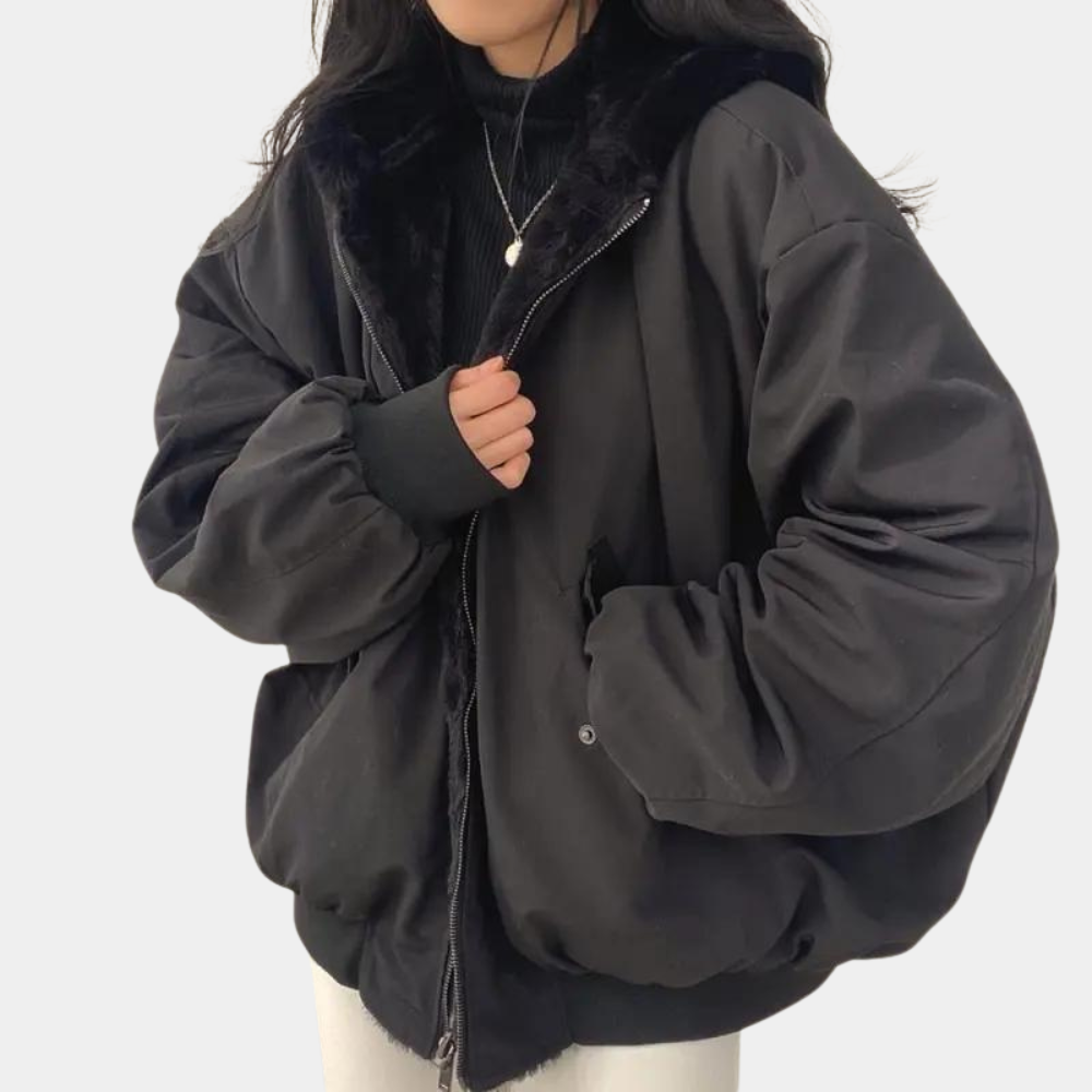 Kvinde iført sort oversized jakke med pelskrave og lynlås, trendy vintermode, casual stil, varm overtøj til kvinder, moderne design.