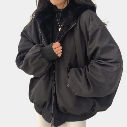 Kvinde iført sort oversized jakke med pelskrave og lynlås, trendy vintermode, casual stil, varm overtøj til kvinder, moderne design.