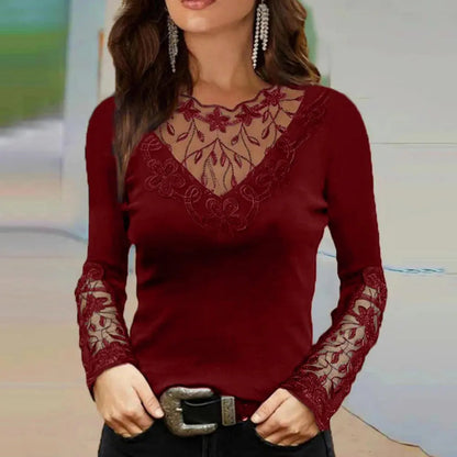 Femme portant un pull bordeaux élégant avec dentelle florale sur le col et les manches, accessoirisé de boucles d'oreilles pendantes et d'une ceinture noire.