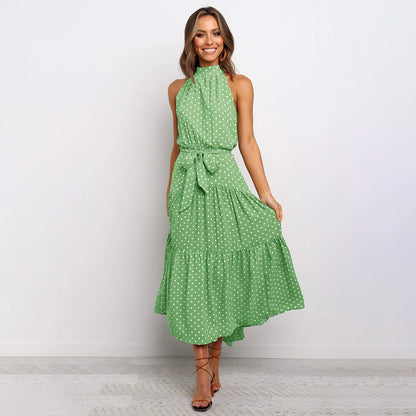 Frau in grüner gepunkteter Maxikleid, ärmellos, mit Gürtel, lächelt, modisch, elegant.
