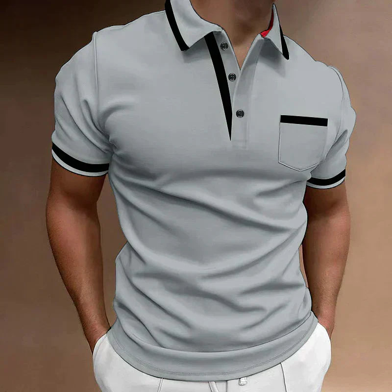 Homme portant un polo gris élégant avec col noir, manches courtes et poche avant, style décontracté chic, mode masculine tendance.