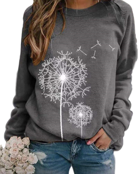 Femme portant un pull gris avec motif pissenlit blanc, tenant un bouquet de roses blanches. Mode décontractée, tendance automne-hiver.