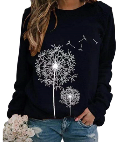 Femme portant un pull noir avec motif pissenlit blanc, tenant un bouquet de roses blanches, vêtue d'un jean décontracté. Mode féminine tendance.