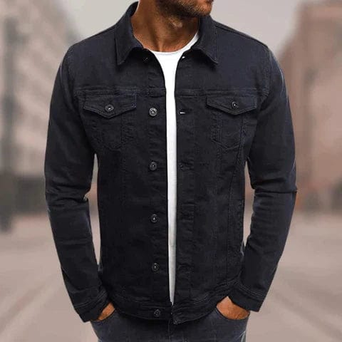 Homme portant une veste en jean noire, style décontracté, sur un t-shirt blanc. Mode masculine, tendance urbaine, arrière-plan flou.