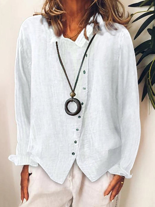 Chemisier blanc en lin pour femme avec col en V, manches longues et boutons verts, accompagné d'un collier pendentif circulaire. Mode élégante et décontractée.