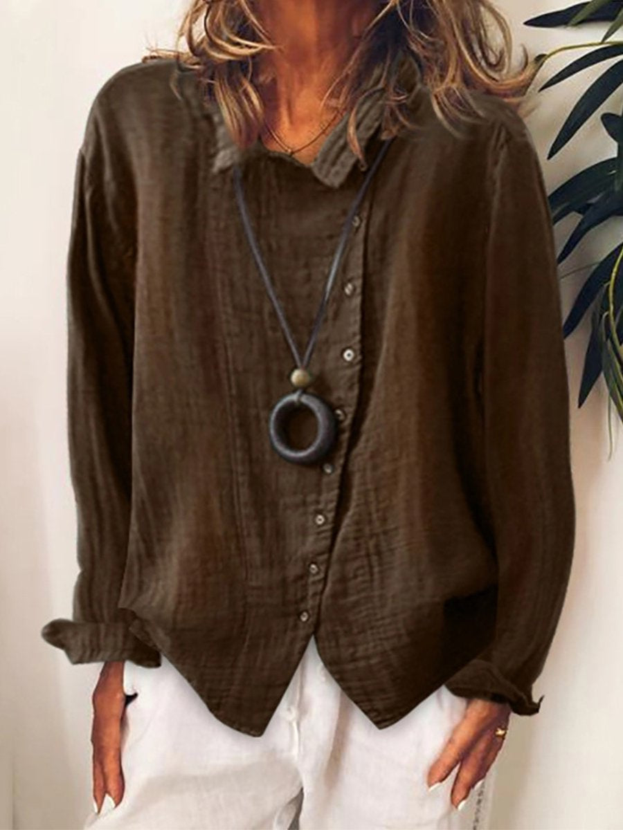 Femme portant une chemise marron en lin avec collier noir, manches longues, devant plante verte. Mode décontractée, style automne-hiver.